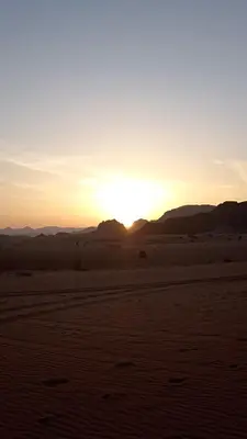 a sunset in the desert with mountains in the background at Wasan Camp Wadi Rum in Wadi Rum
