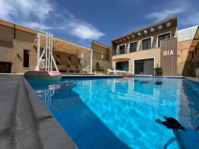 a large swimming pool with blue water in front of a building at Oia chalet in Ash Shāghūr