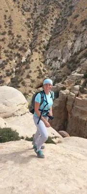 a woman with a backpack standing on a mountain at Camping in Dana in At-Tafilah