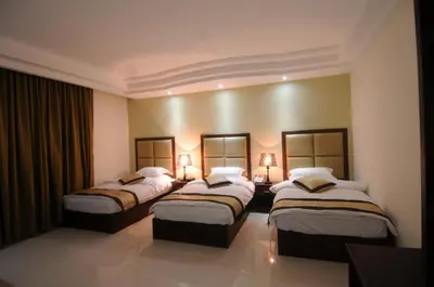a hotel room with three beds and two lamps at Tetra Tree Hotel 1 in Wadi Musa