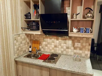 a kitchen counter with a sink and a tv at Easy Inn Hotel Suites in Amman
