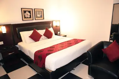 a bedroom with a large bed and a chair at Easy Inn Hotel Suites in Amman
