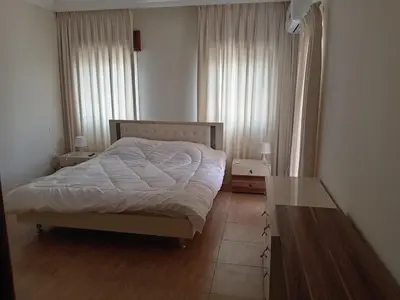 a bedroom with a bed and two windows and a table at Stay with Saja Room in Weibdeh in Jurf ad Darāwīsh