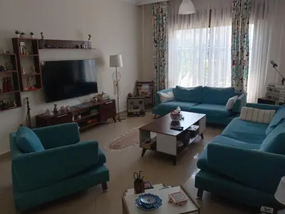 a living room with blue couches and a tv at Stay with Saja Room in Weibdeh in Jurf ad Darāwīsh