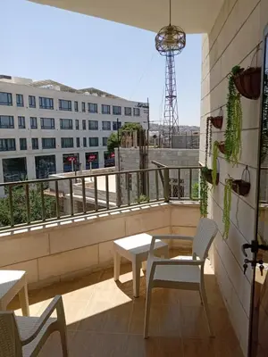 a balcony with a table and chairs and a building at Stay with Saja Room in Weibdeh in Jurf ad Darāwīsh