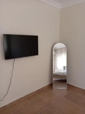a flat screen tv hanging on a wall with a mirror at Stay with Saja Room in Weibdeh in Jurf ad Darāwīsh