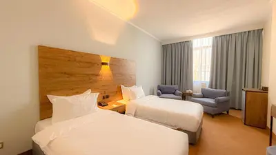 a hotel room with two beds and a chair at Aqaba Gulf Hotel By FHM in Aqaba