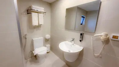 a white bathroom with a toilet and a sink at Aqaba Gulf Hotel By FHM in Aqaba