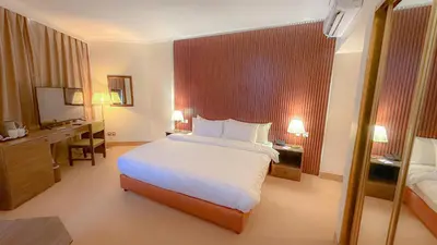 a bedroom with a large white bed and a desk at Aqaba Gulf Hotel By FHM in Aqaba