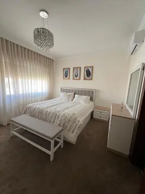 a white bedroom with a bed and a table at Modern Luxe Getaway in Amman