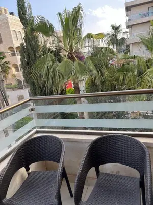 two chairs sitting on a balcony with palm trees at Modern Luxe Getaway in Amman