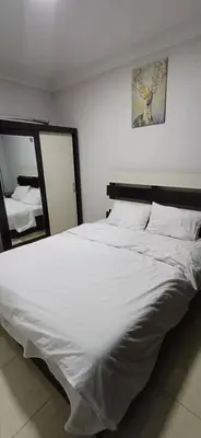 a large white bed in a bedroom with a mirror at شقق الجبيهة العائلية in Amman
