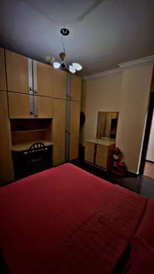 a bedroom with a red bed and wooden cabinets at شقه مفروشه in Jurf ad Darāwīsh