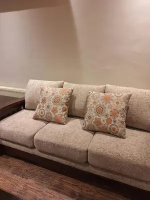 a brown couch with four pillows on it at شقه مفروشه in Jurf ad Darāwīsh