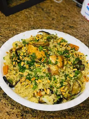 a plate of food with chicken and rice on a table at الصدقه ان in Aş Şadaqah