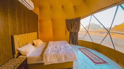 a bedroom with a bed and a large window at Wadi Rum Sha ar Nights in Wadi Rum