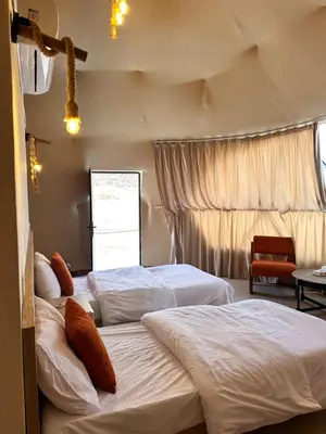 a bedroom with two beds and a window at Wadi Rum Sha ar Nights in Wadi Rum