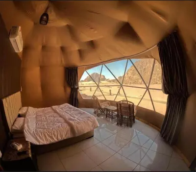 a bedroom with a bed and a large window at Wadi Rum Sha ar Nights in Wadi Rum