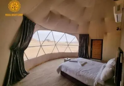 a bedroom with a large bed with a large window at Wadi Rum Sha ar Nights in Wadi Rum