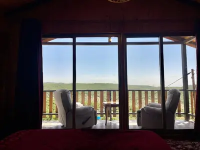 a bedroom with two chairs and a view of a balcony at كوخ واستراحة شيخ الجبل in Ajloun