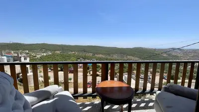 a balcony with a table and chairs and a view at كوخ واستراحة شيخ الجبل in Ajloun