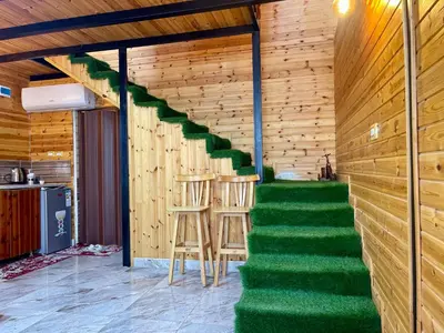 a staircase in a wooden house with green carpet at كوخ واستراحة شيخ الجبل in Ajloun
