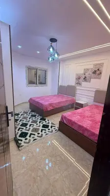 a bedroom with two beds with pink sheets and a rug at صبحه هاوس in Şabḩā