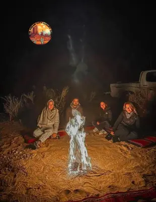 a group of people sitting around a fire at night at RUM DREAM CITY lUXURY CAMP in Wadi Rum
