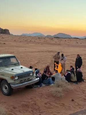 a group of people sitting around a fire in the desert at Wadi Rum Desert Experience in Wadi Rum