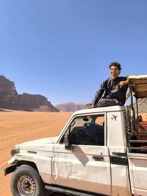 a man sitting on the back of a white truck in the desert at Wadi Rum Cave Experience in Wadi Rum