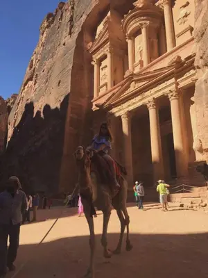 a woman riding a camel in front of a building at man -soor in Amman