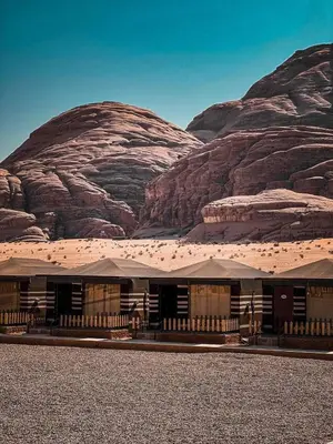 a building in the desert with mountains in the background at Wadi rum camp hamod in Wadi Rum