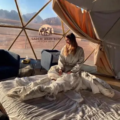 a woman sitting on a bed in a tent at SADEM WADl RUM in Wadi Rum