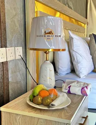 a table with a lamp on top of a bed at SADEM WADl RUM in Wadi Rum