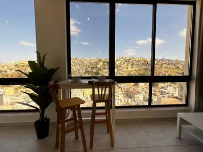 a table and two chairs in a room with a large window at Central Amman Stunning Views Apt in Amman