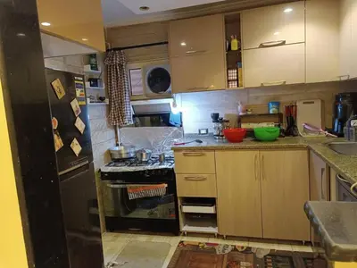 a kitchen with wooden cabinets and a black refrigerator at بليله هاوس in Balīlā