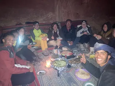 a group of people sitting around a table with food at Wadi Rum Starlit in Wadi Rum