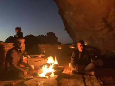 a group of three men sitting around a fire at Wadi Rum Starlit in Wadi Rum