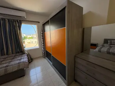 a bedroom with a bed and a dresser and a window at Al-Amer شقق الخامسه الراقيه in Aqaba