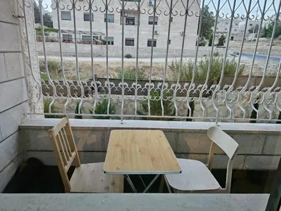 a table and two chairs on a balcony with a window at شقة 3غرف نوم في ضاحية الرشيد in Amman
