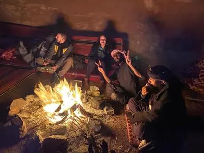 a group of people sitting around a fire at Wadi Rum Starlit in Wadi Rum