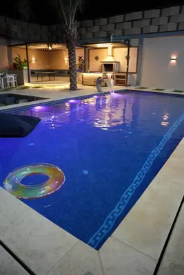 a large swimming pool with blue water in a building at Lumen villa in Umm Uthainah