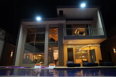 a house with a swimming pool at night at Lumen villa in Umm Uthainah
