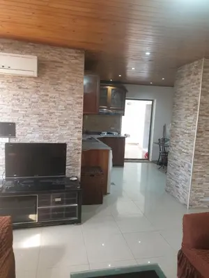 a living room with a tv and a brick wall at الاردن عمان تلاع العلي شارع ابو يوسف الأنصاري اسكان طارق الشيخ in Amman