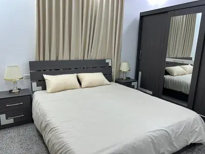 a bedroom with a large white bed with two lamps at Raha's house in Jerash