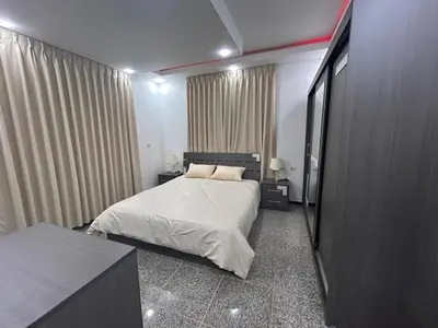 a bedroom with a bed and two tables and curtains at Raha's house in Jerash