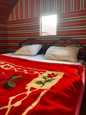 a bed with a red blanket and two pillows at Rum Sky Experiences in Wadi Rum