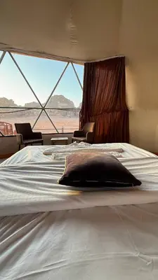 a large bed in a room with a large window at Tarf Wadi Rum Luxury Camp & Jeep Tours in Wadi Rum