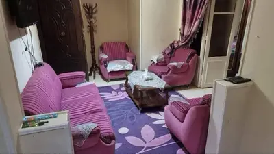 a living room with purple chairs and pink couches at ام الدنانير هاوس in Rujm al Ḩāwī