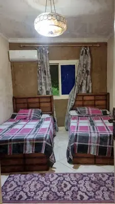 a bedroom with two beds and a chandelier at ام الدنانير هاوس in Rujm al Ḩāwī